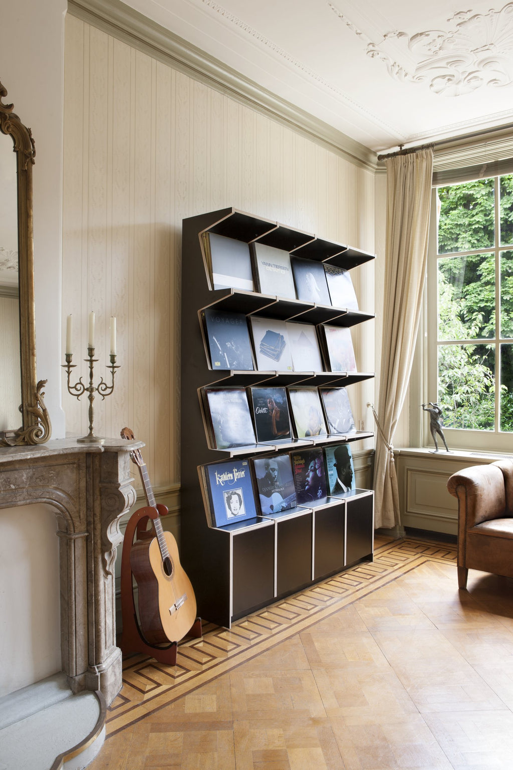 Black Coverfront record cabinet seen at an angle beside a window, records displayed cover-forward