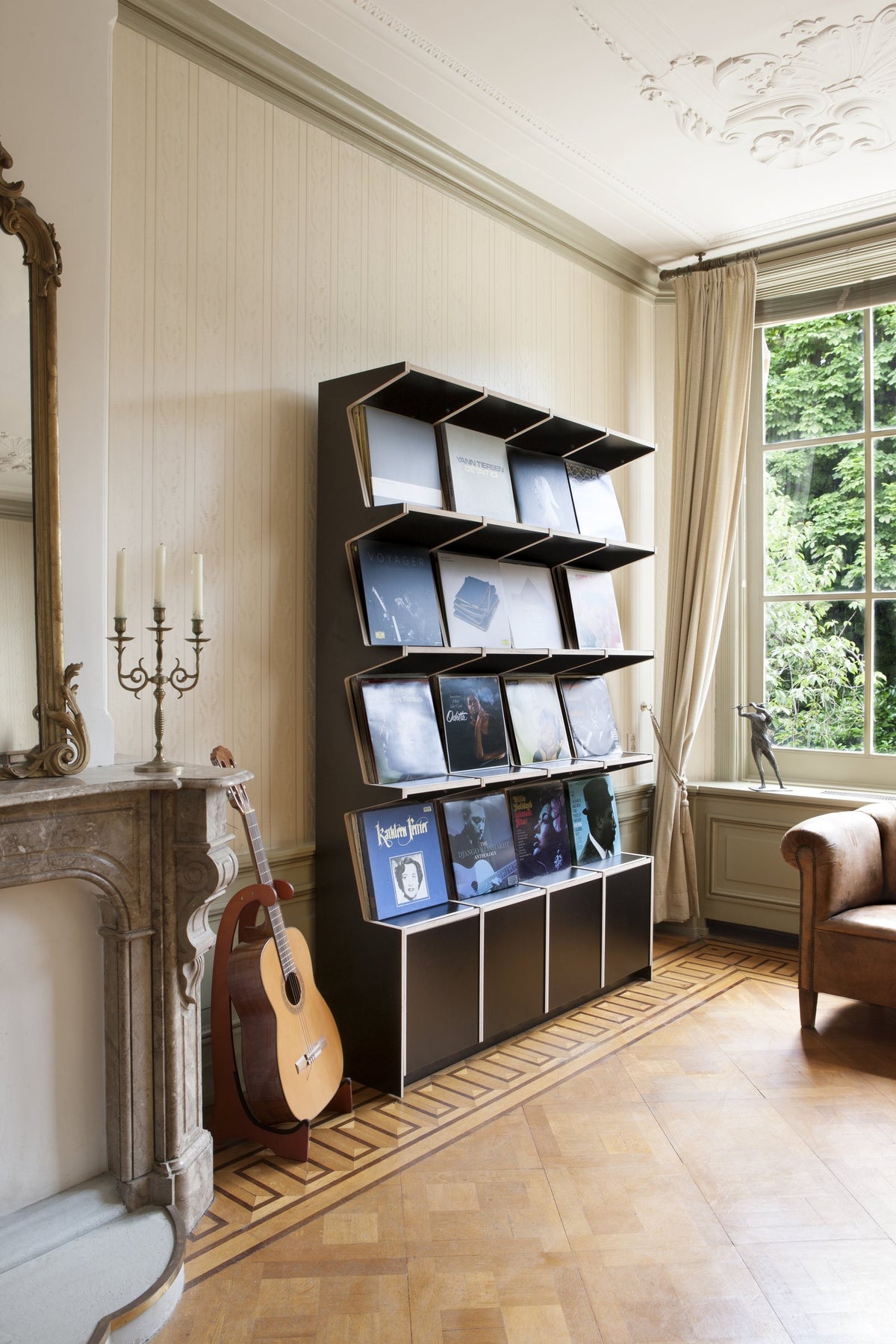 Black Coverfront record cabinet seen at an angle beside a window, records displayed cover-forward